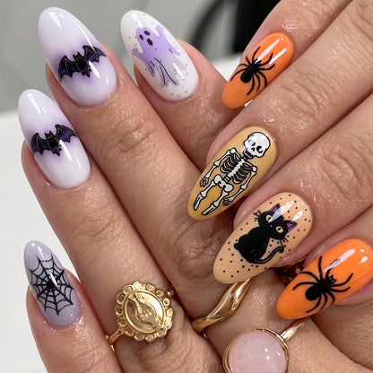 Close-up hand showing Halloween oval long nails with bat, ghost, spider, skull, cat in purple, white, orange, yellow