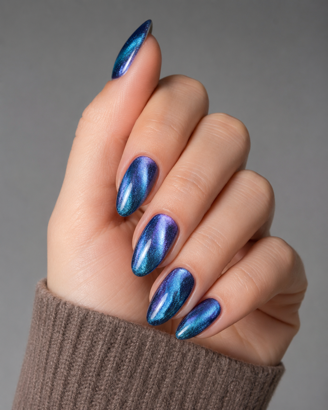 Aurora Blue Cat Eye almond press-on nails worn on a hand