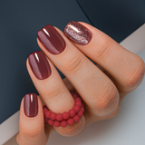 Burgundy Bling short squoval press-on nails worn on a hand