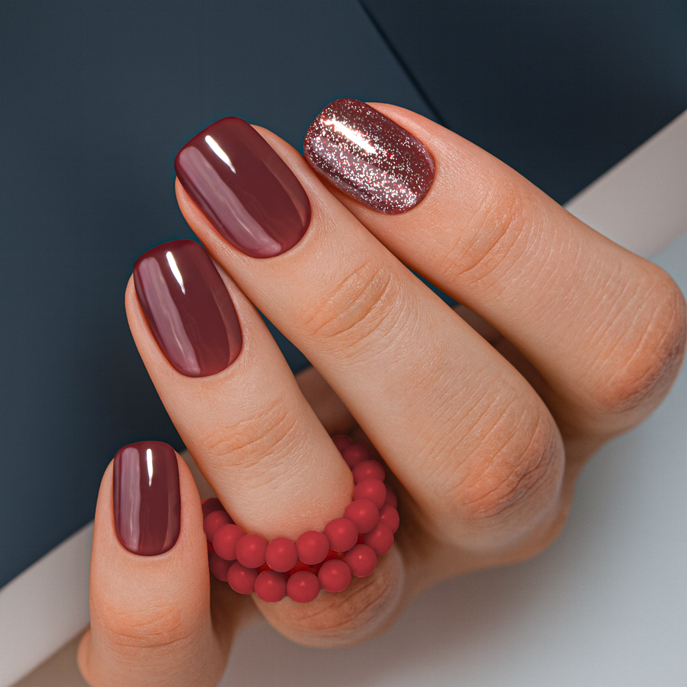 Burgundy Bling short squoval press-on nails worn on a hand