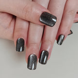 Charcoal Glitter short squoval press-on nails worn on a hand