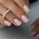 Classic Nude short squoval press-on nails worn on a hand