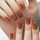 Cocoa Brick short squoval press-on nails worn on a hand