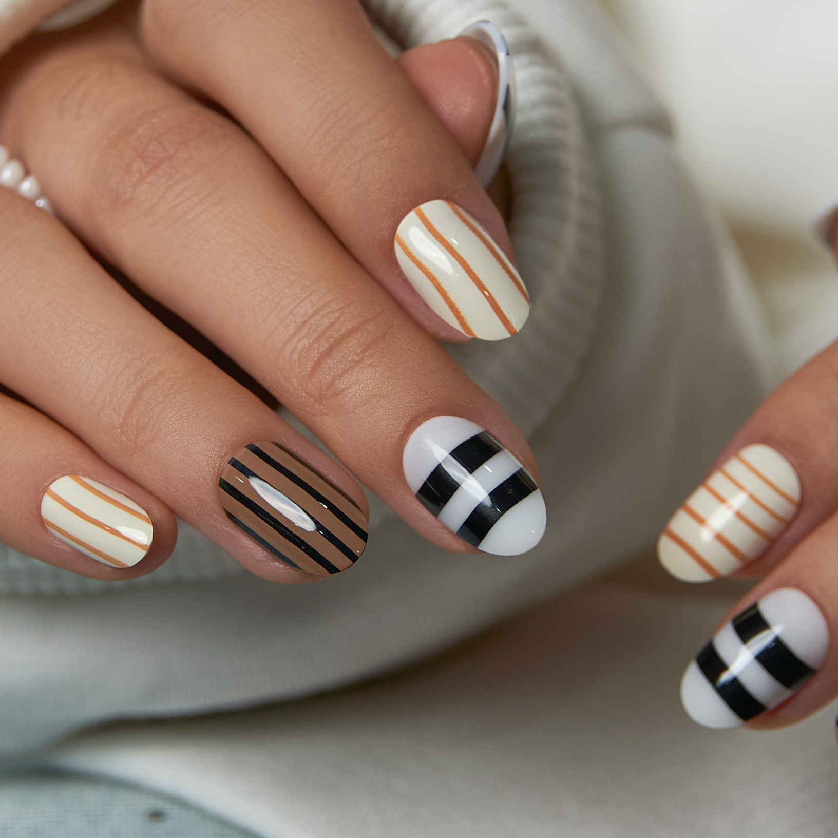 Coffee Line short oval press-on nails worn on a hand