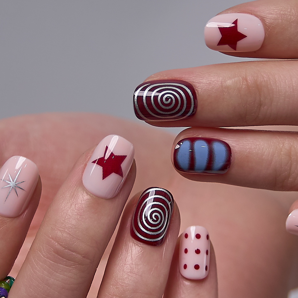 Crimson Swirl Rs squoval press-on nails worn on a hand
