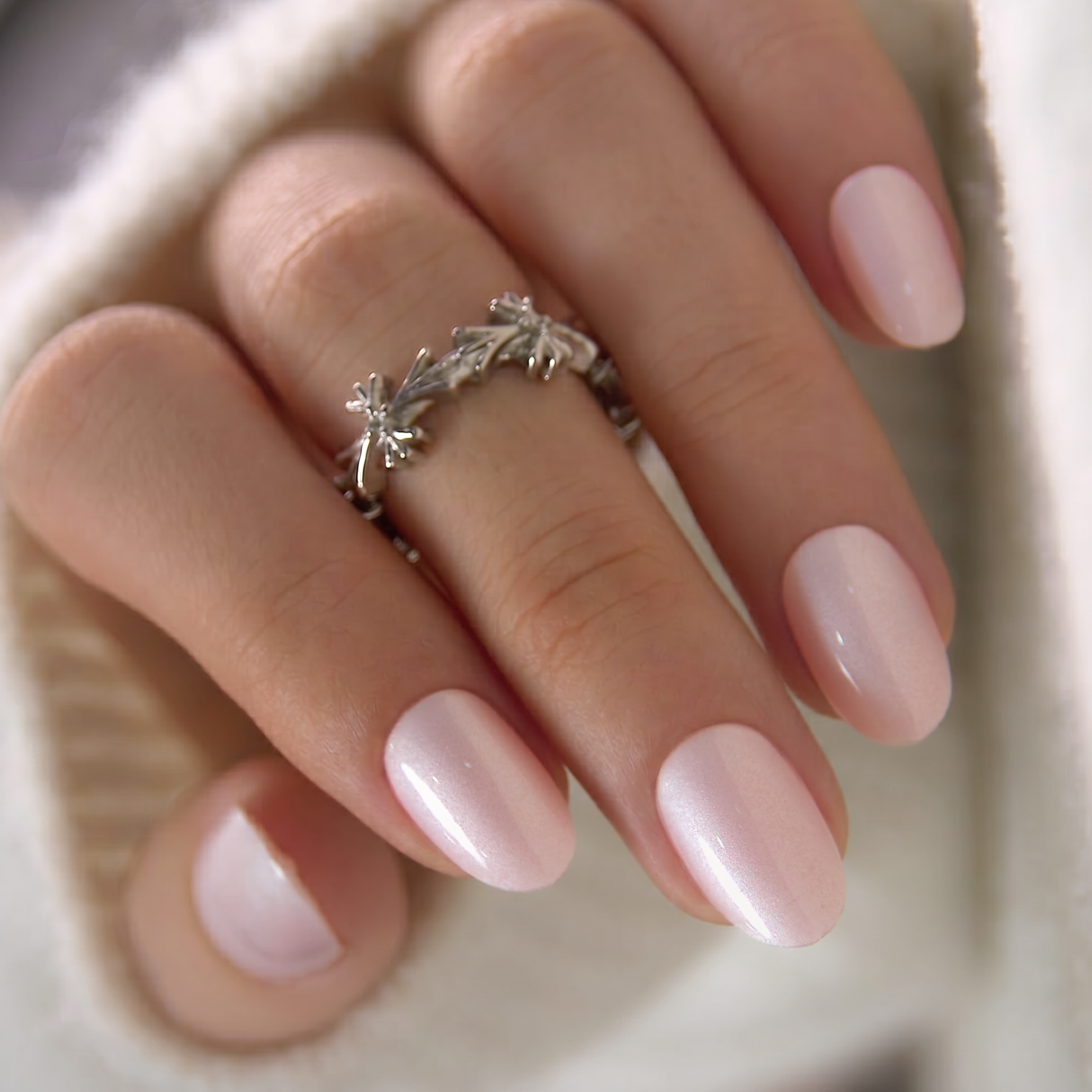 Delicate Glow short oval press-on nails worn on a hand