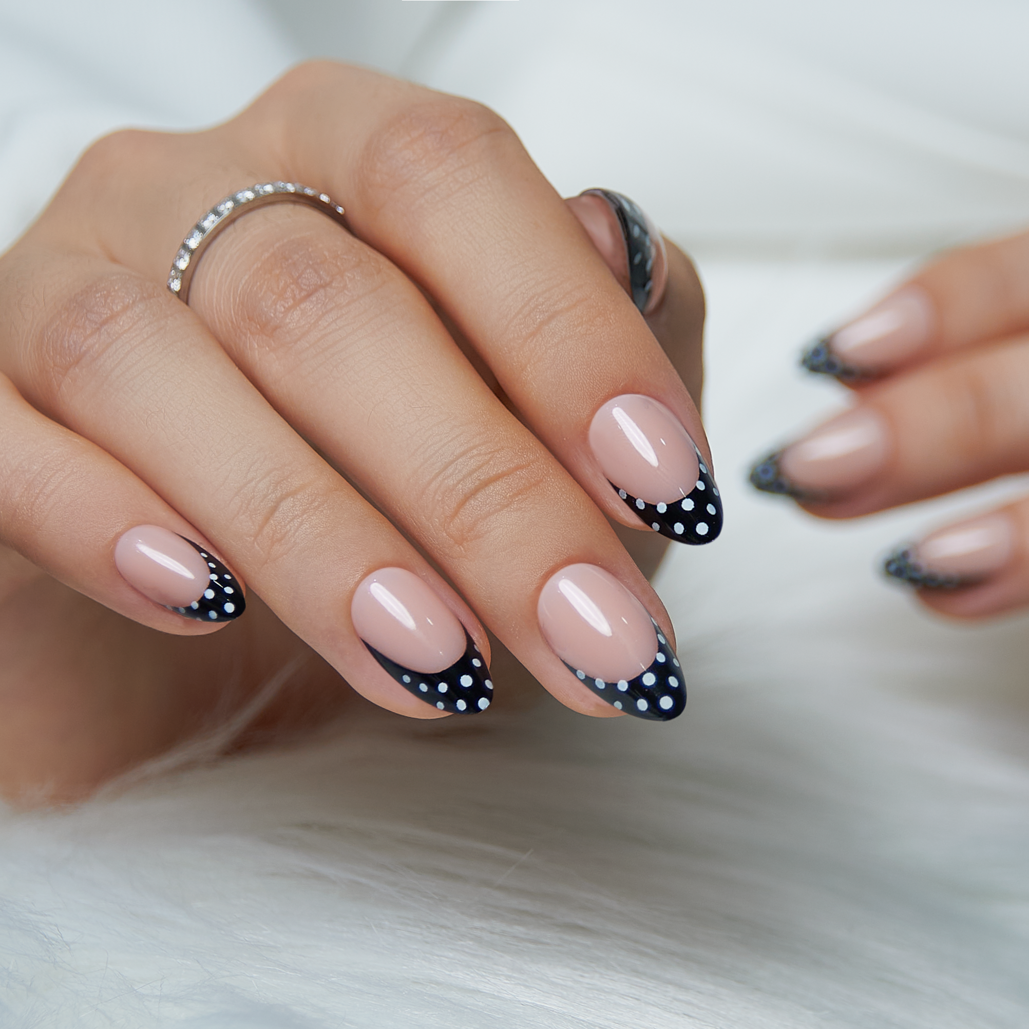 Dot Noir short almond press-on nails worn on a hand