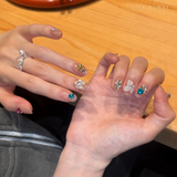 Lirenail press-on nails detail with nude base, white 3D flowers and blue heart-shaped crystal accents