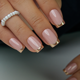 Golden French medium squoval press-on nails worn on a hand