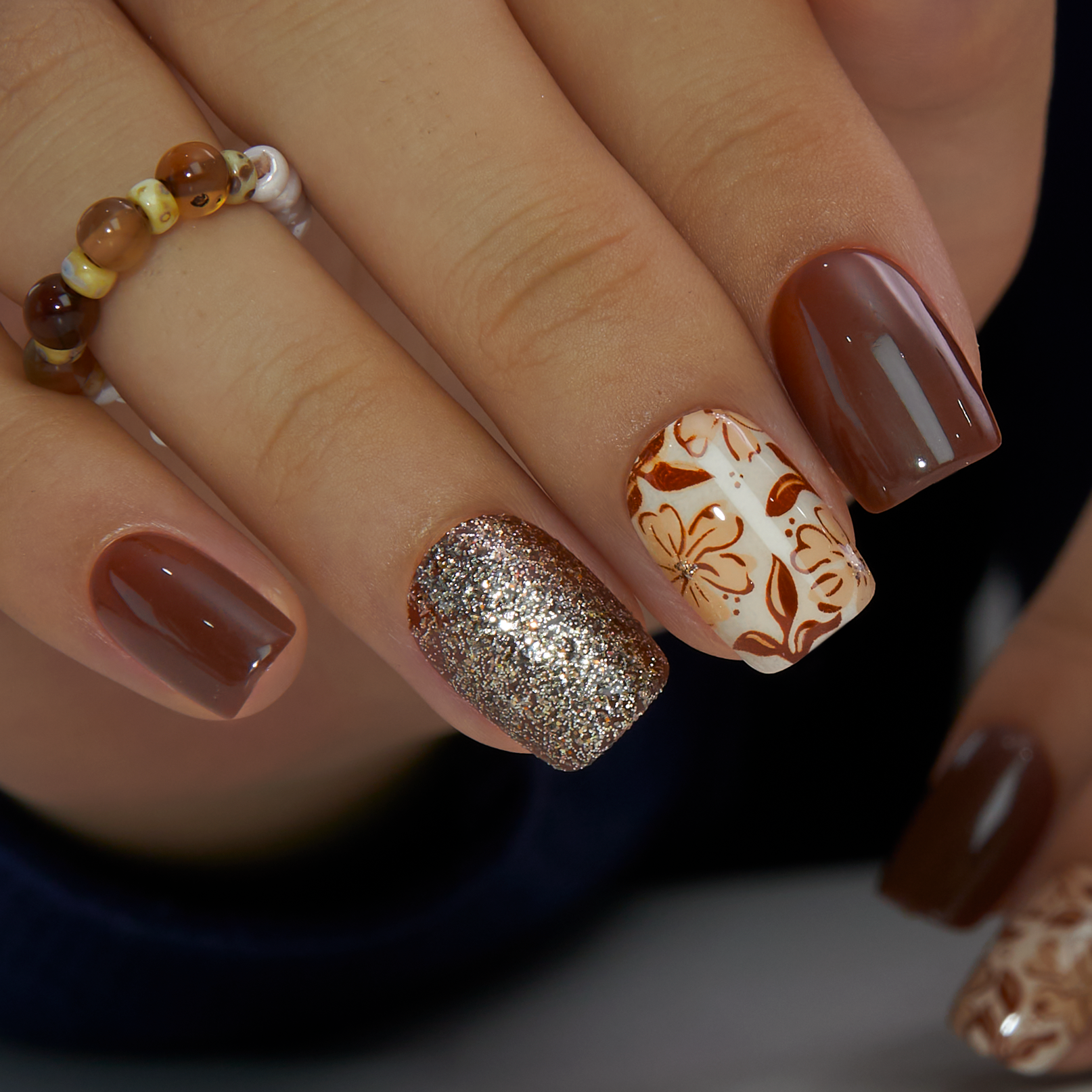 Golden Mocha short squoval press-on nails worn on a hand