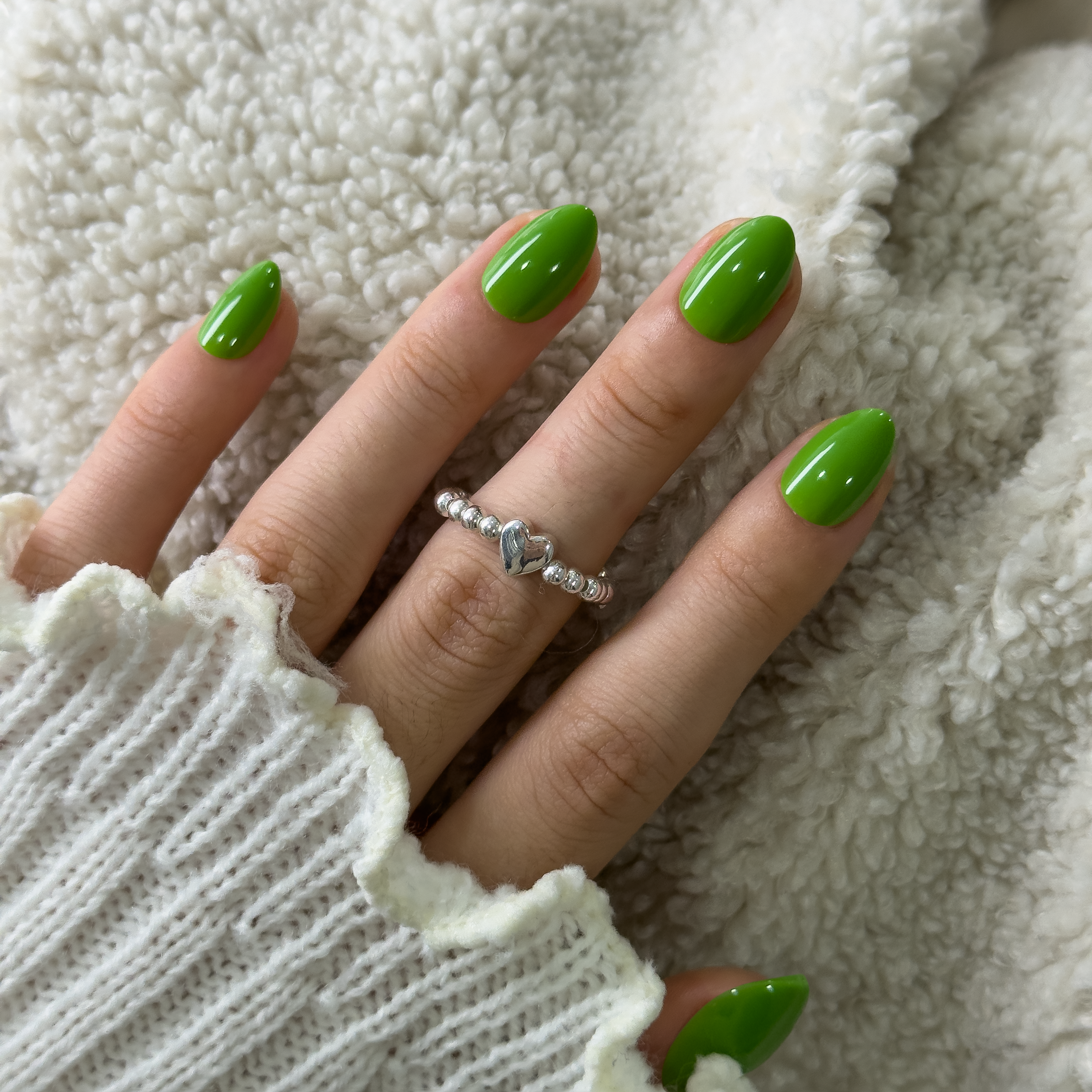 Green Muse Rs almond press-on nails worn on a hand