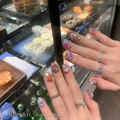 Half-Sugar Promise press-on nails worn on hands with pink-purple base, colorful gems and heart charm accents