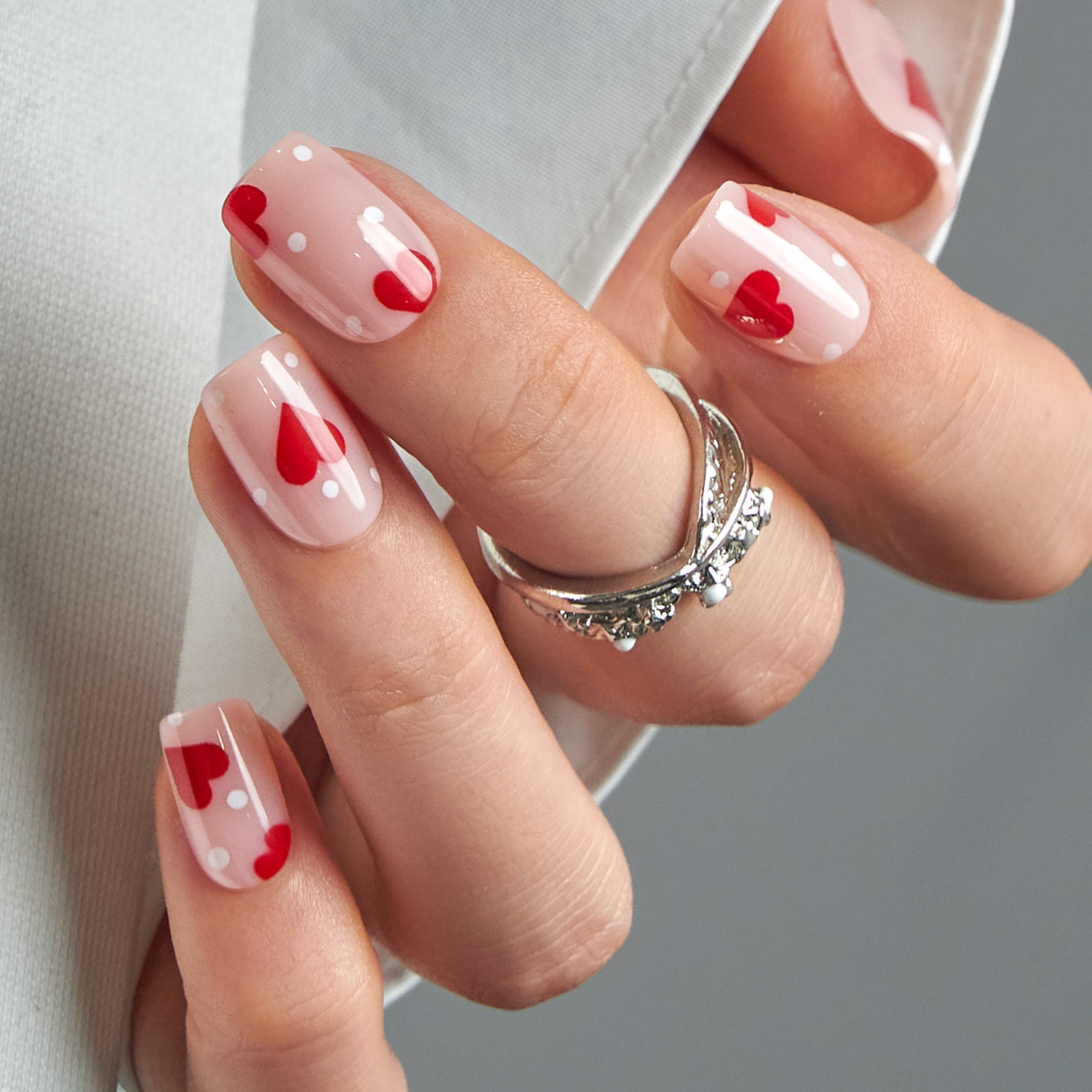 Heart Polka short squoval press-on nails worn on a hand
