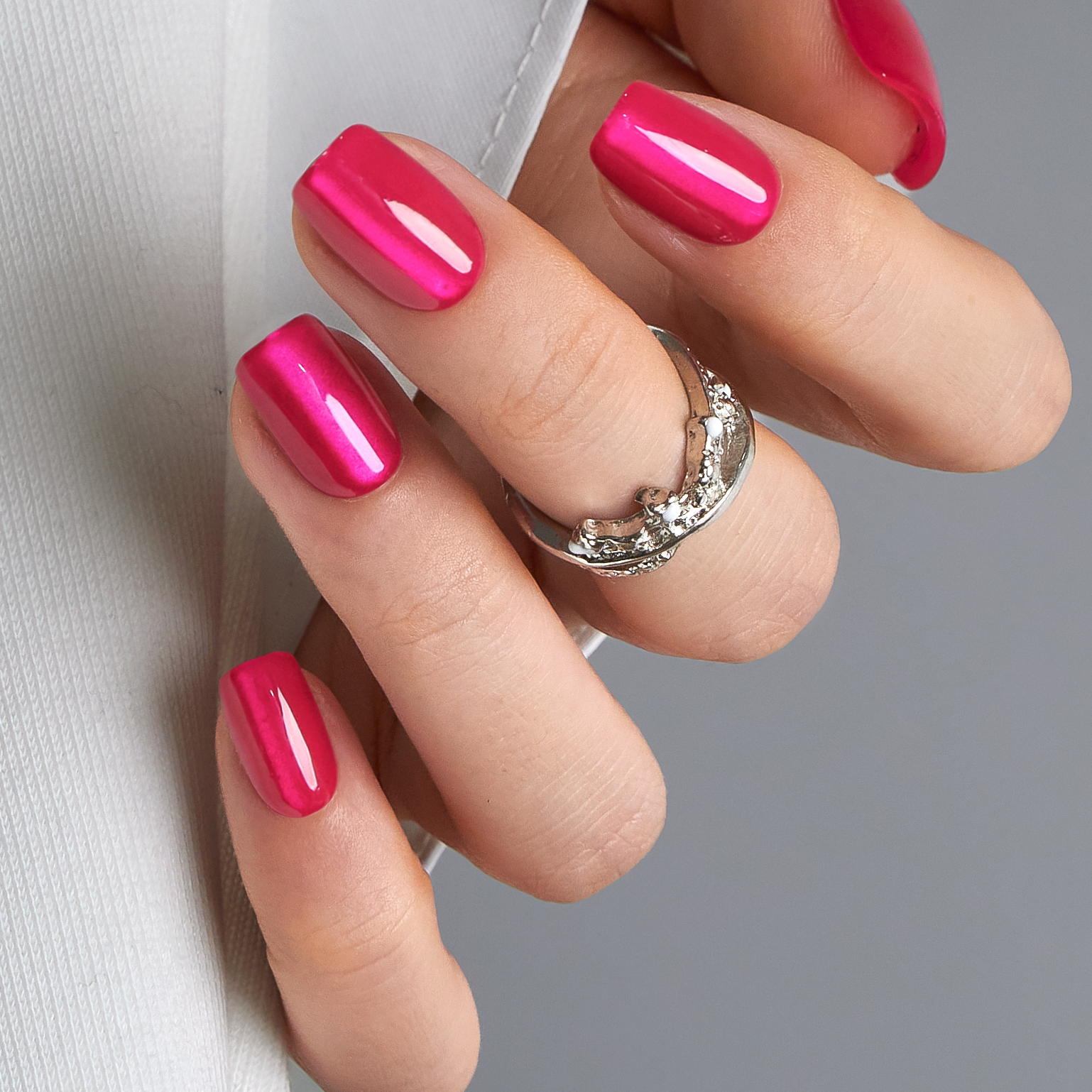 Hot Fuchsia short squoval press-on nails worn on a hand