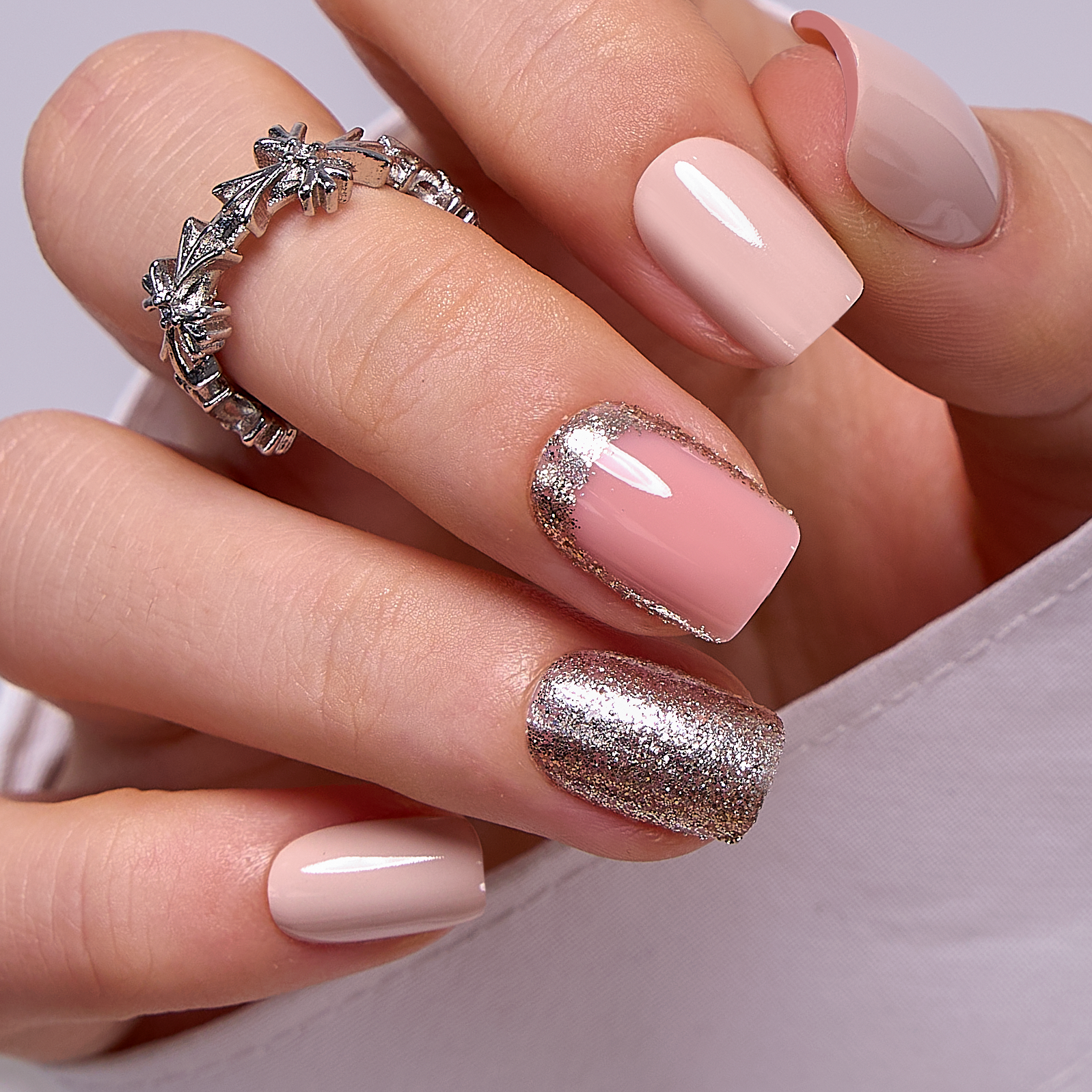 Light Pink Gold short squoval press-on nails worn on a hand