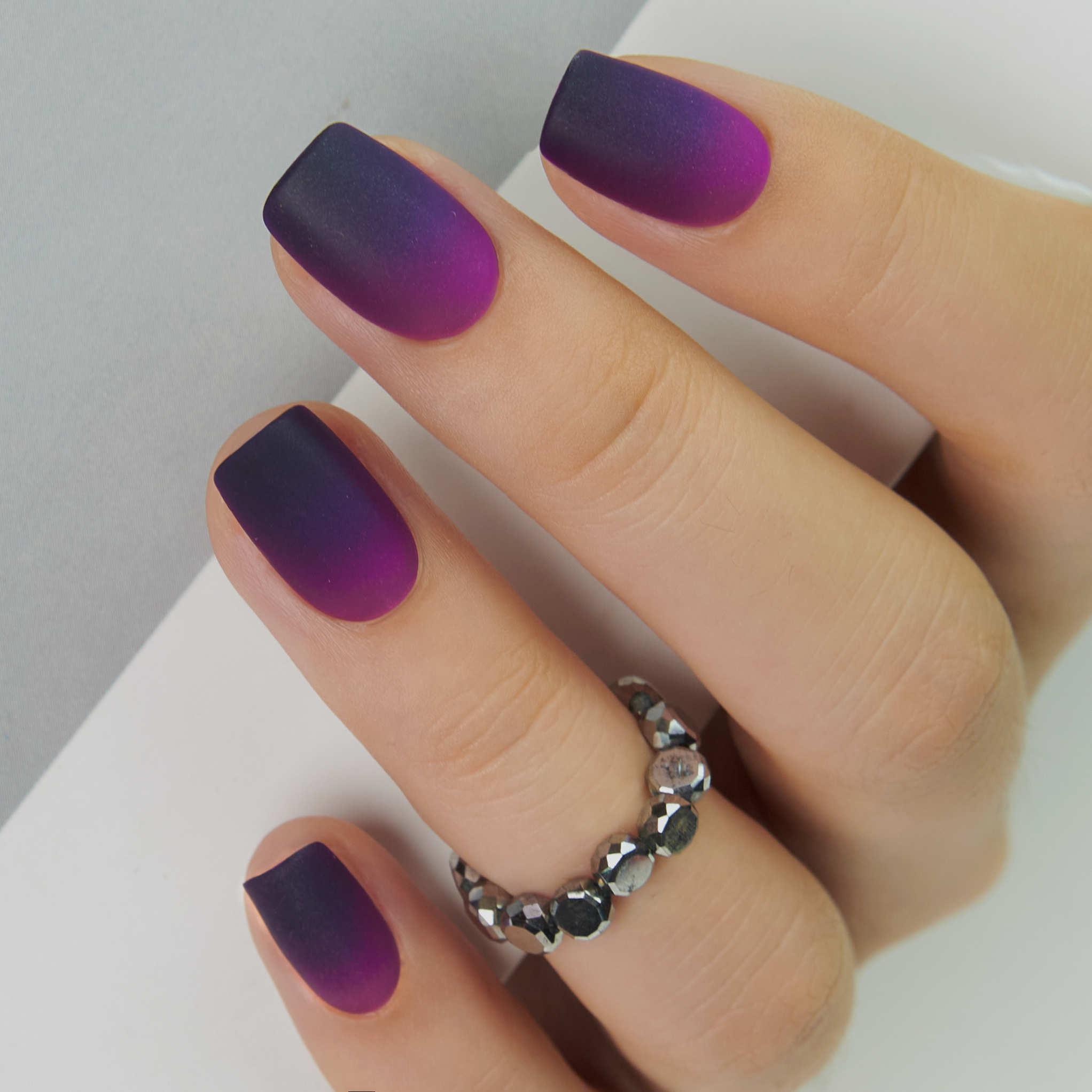 Matte Purple short squoval press-on nails worn on a hand