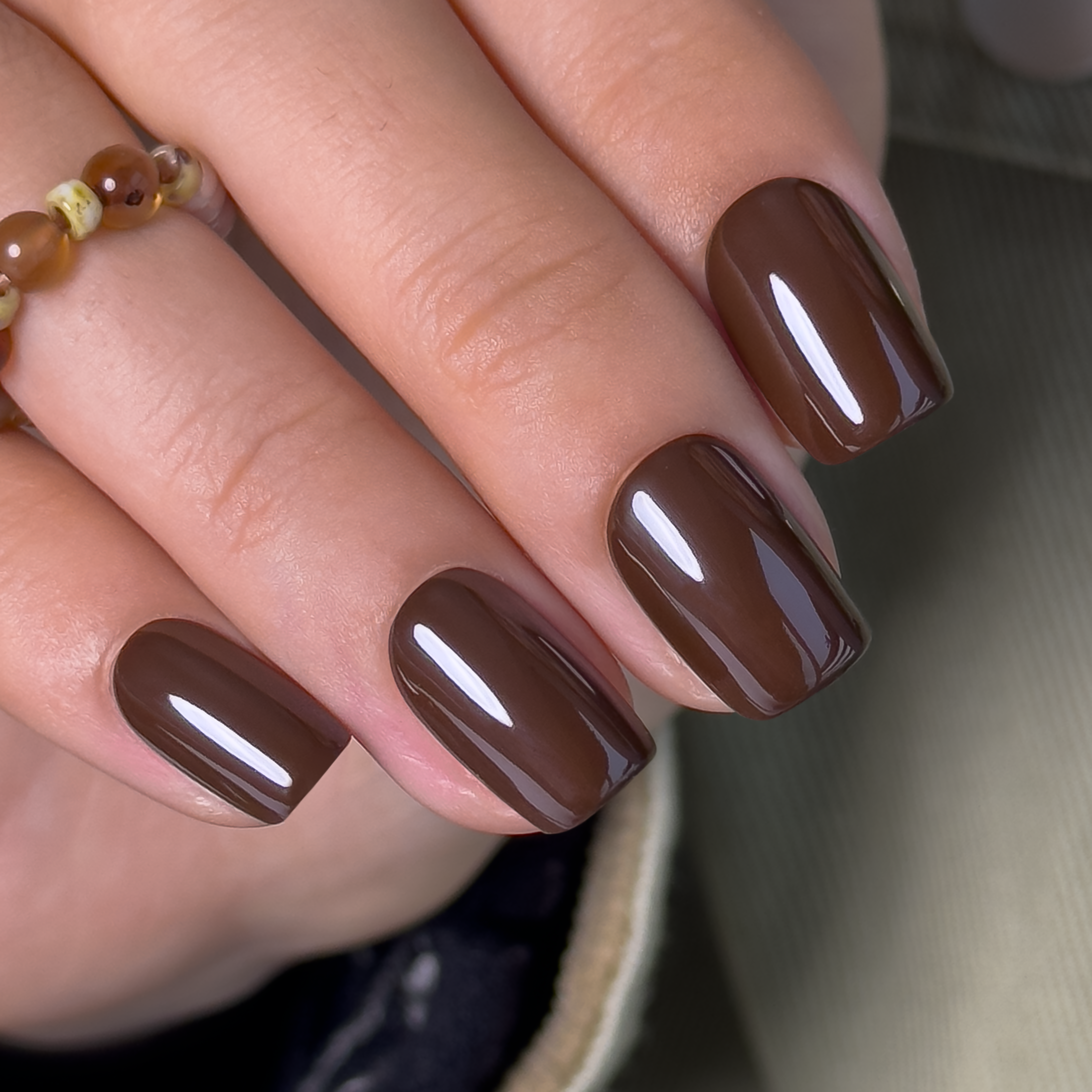 Mocha Essence short squoval press-on nails worn on a hand