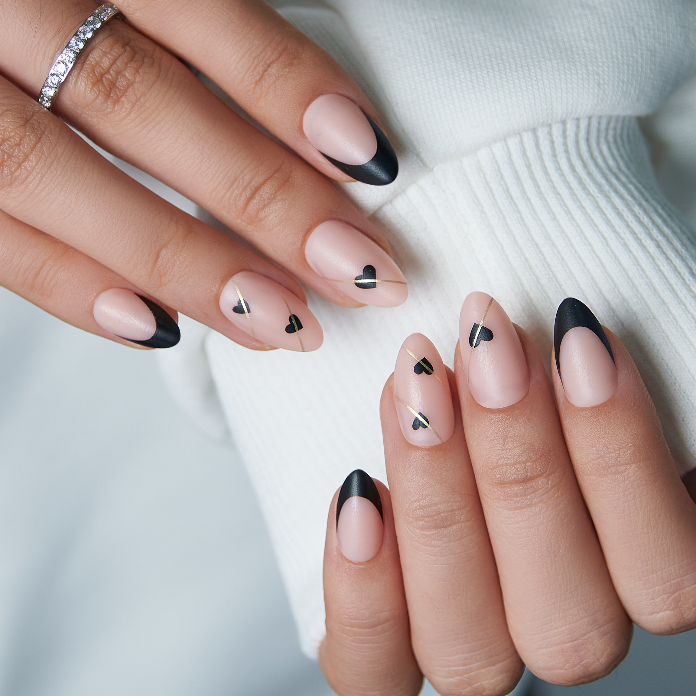 Noir Cupid short almond press-on nails worn on a hand
