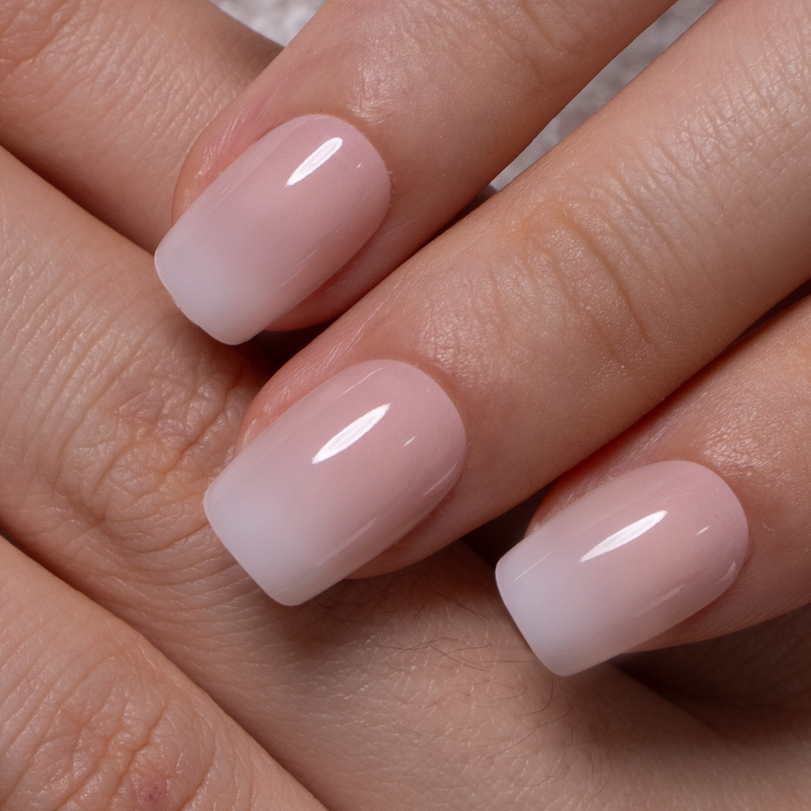 Nude Ombre short squoval press-on nails worn on a hand
