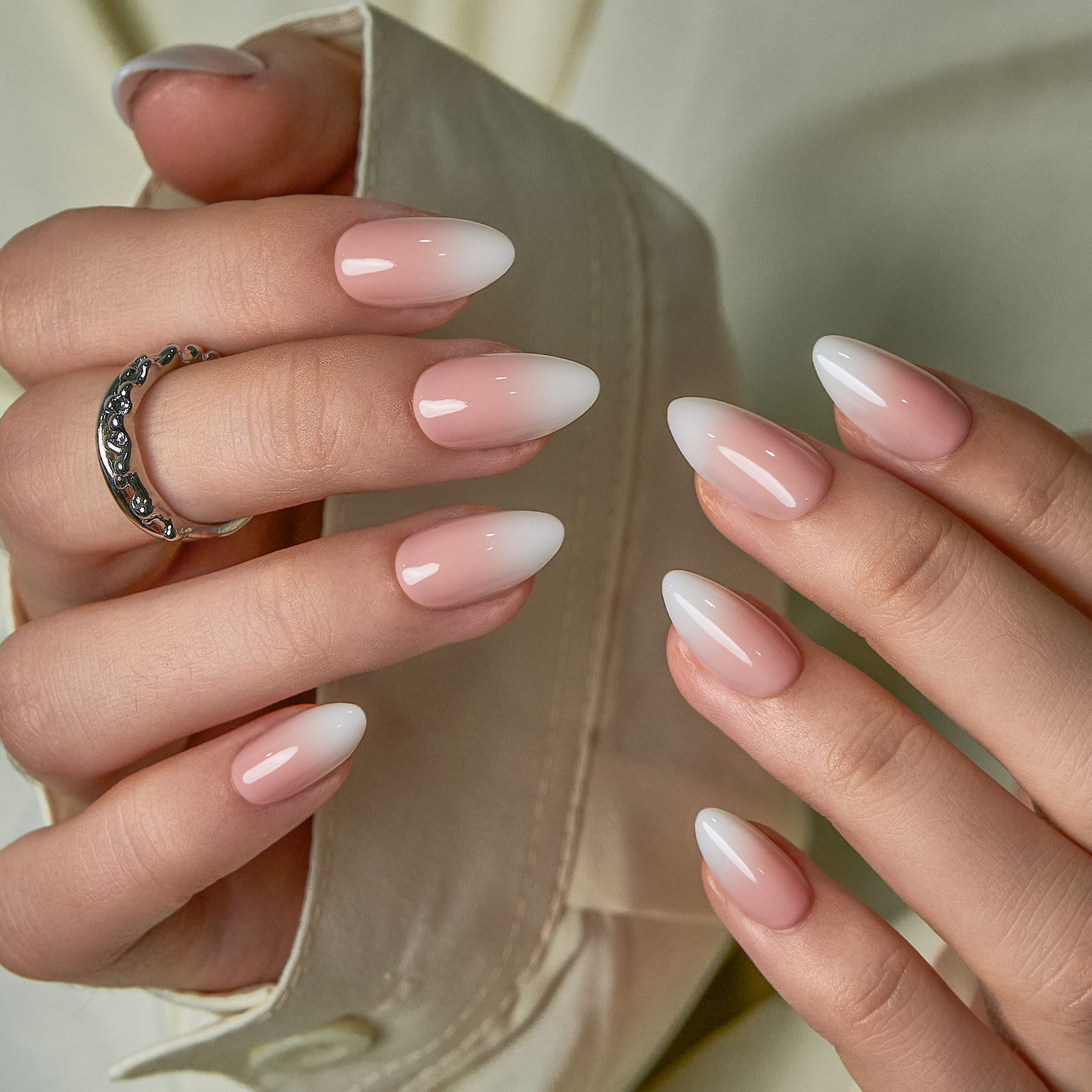 Nude Tips short almond press-on nails worn on a hand