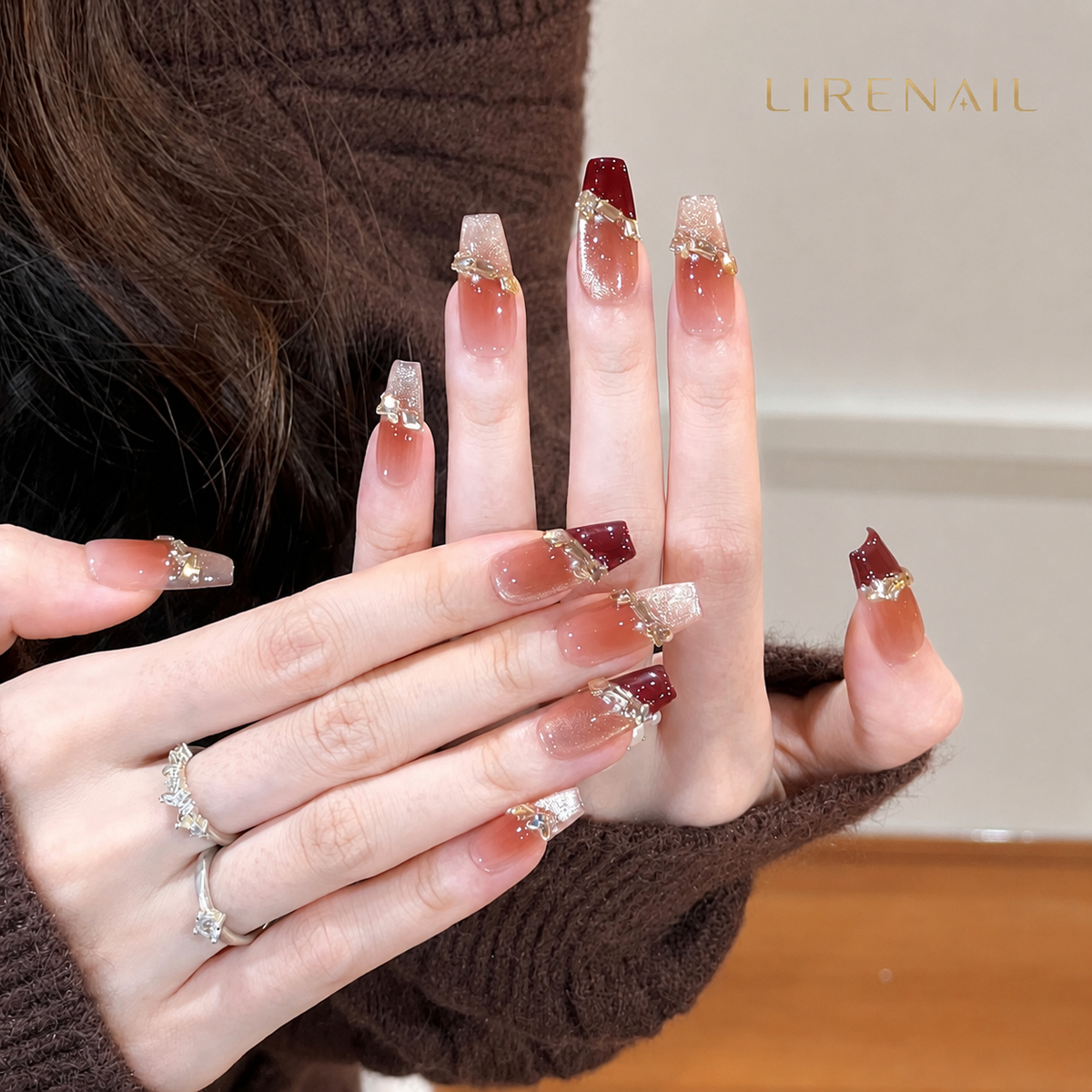Opal Charm press-on nails worn showing gradient pink-brown base with burgundy French tip and bow accent