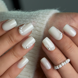 Pearl Drizzle short squoval press-on nails worn on a hand