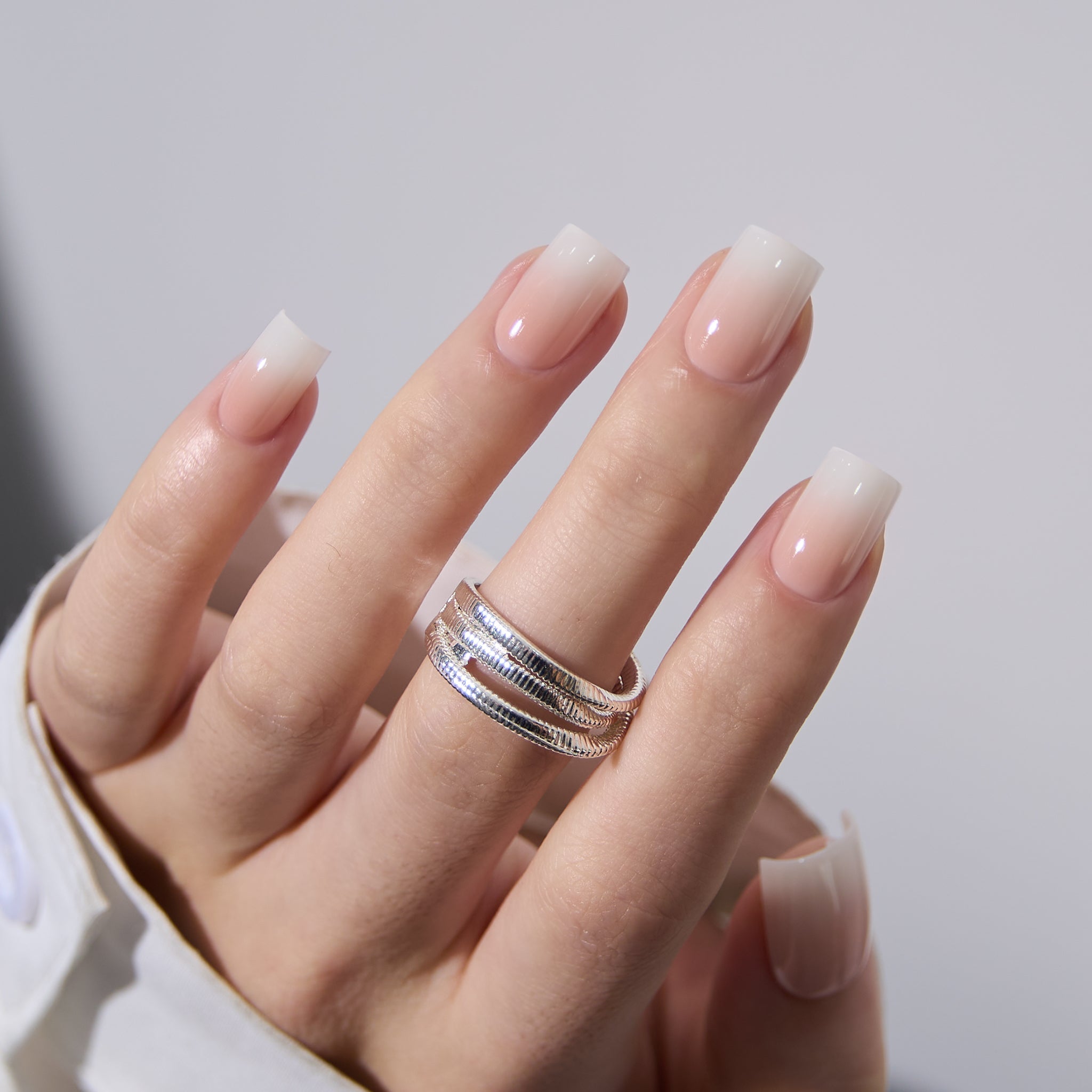 Pink And White short square press-on nails worn on a hand