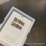 Rainbow Fairy Brown press-on nails packaging with brown tones, colorful gems, heart and mushroom charms