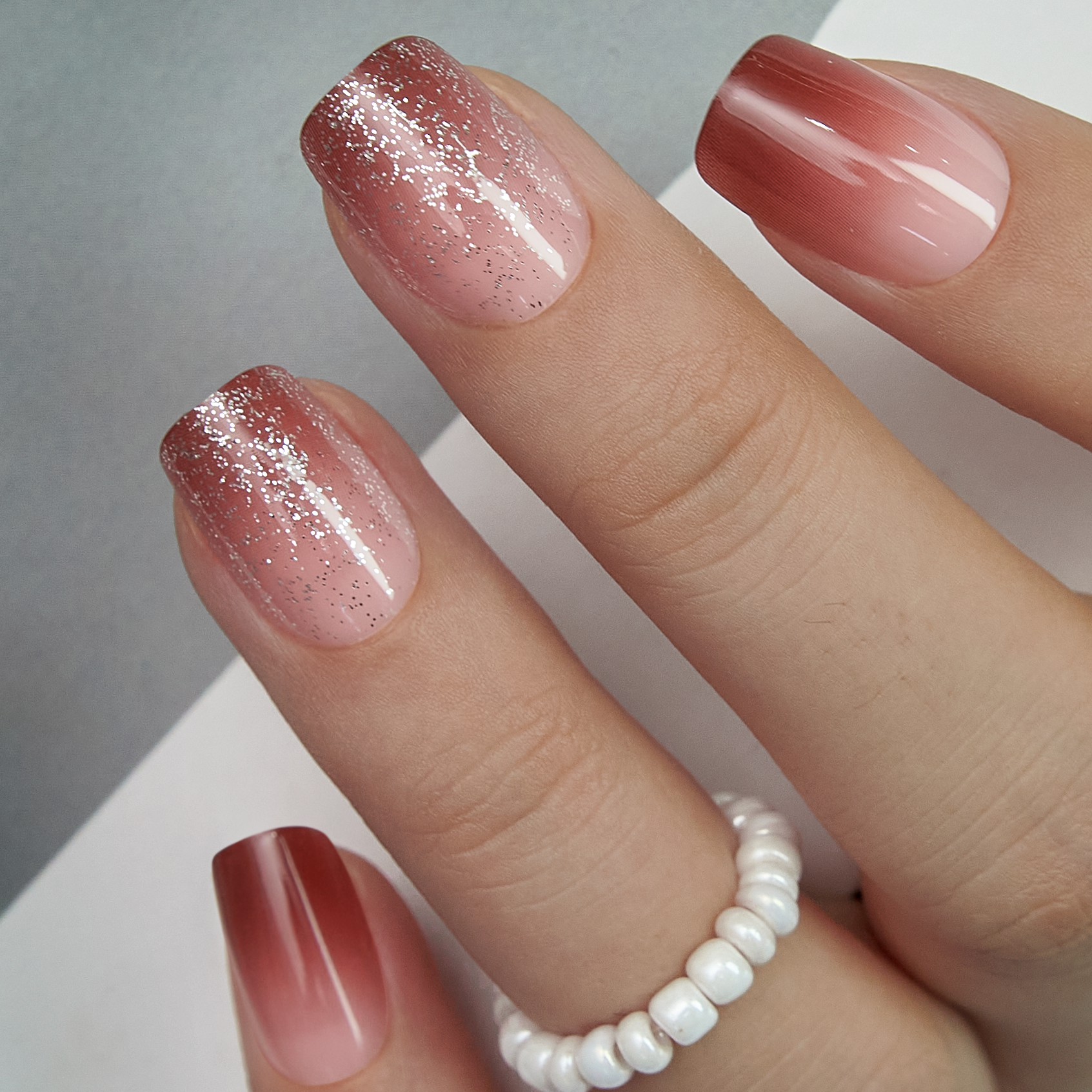 Rosewood Glide short squoval press-on nails worn on a hand