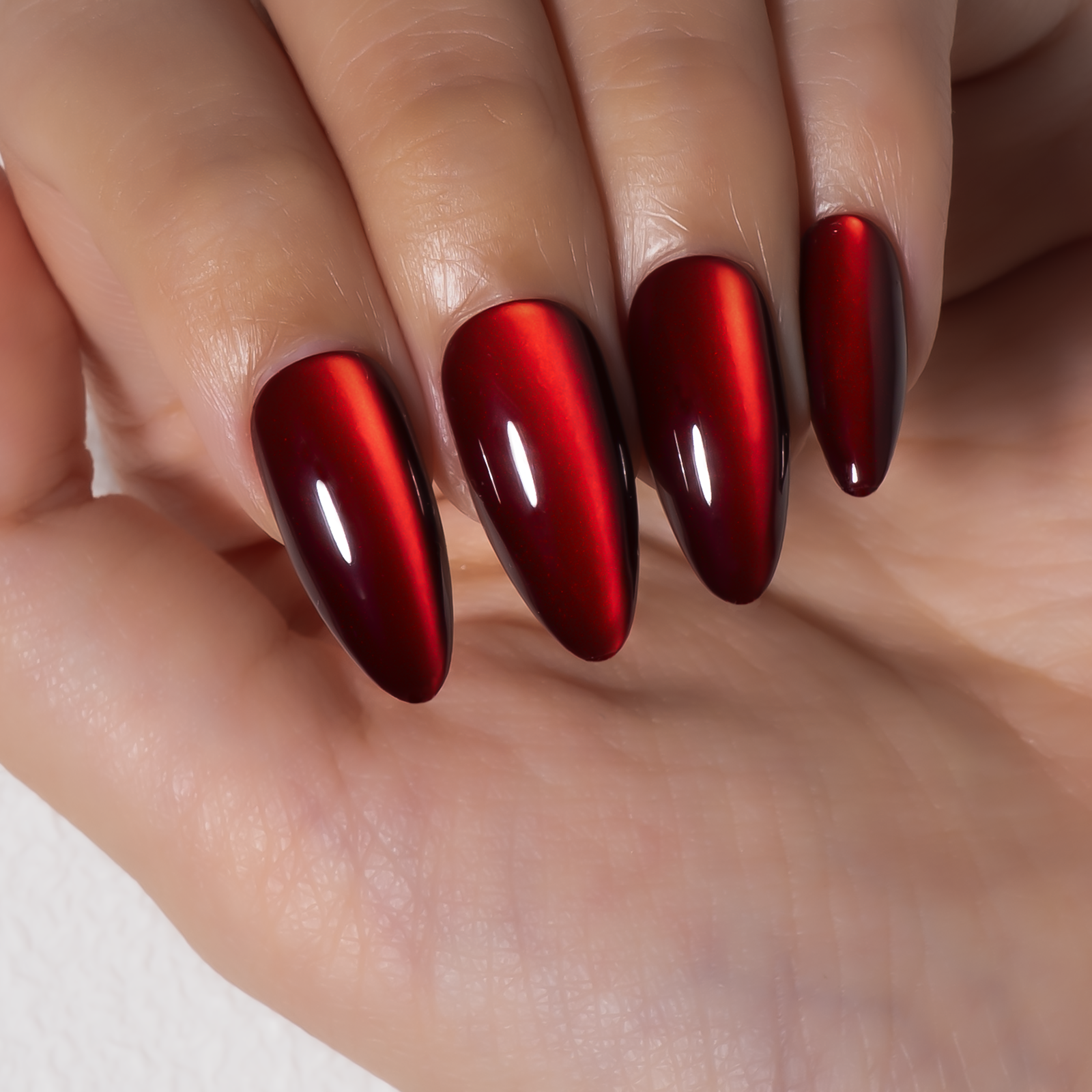 Ruby Cat Glow long almond press-on nails worn on a hand