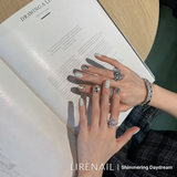 Shimmering Daydream press-on nails worn on hands with grey-cream base and square crystal accents