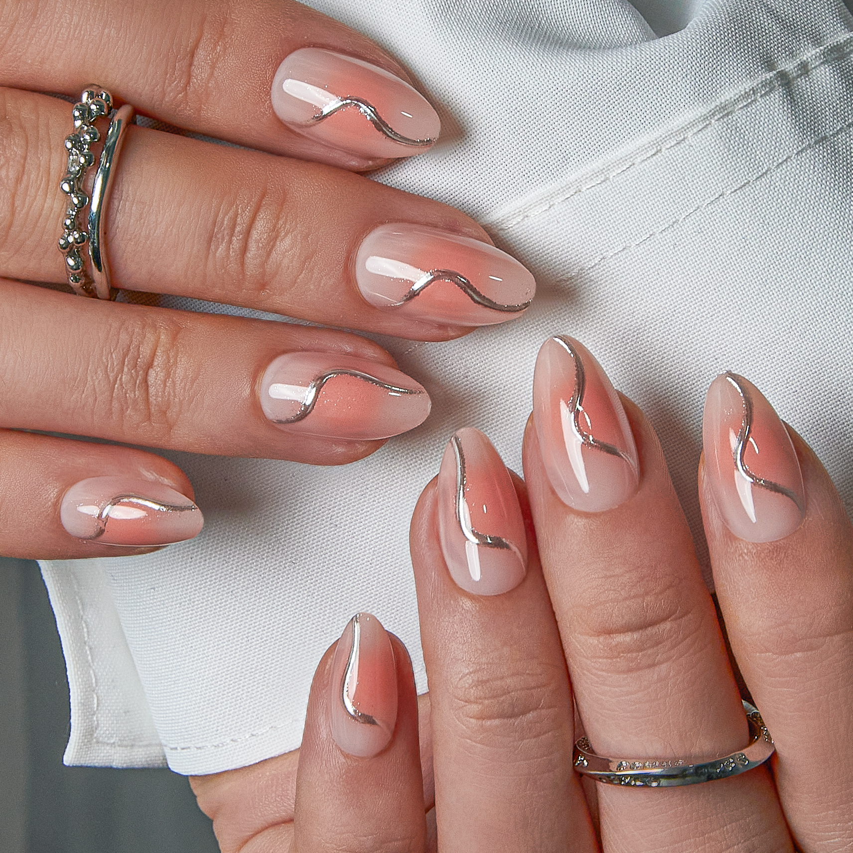 Silver Wave short almond press-on nails worn on a hand