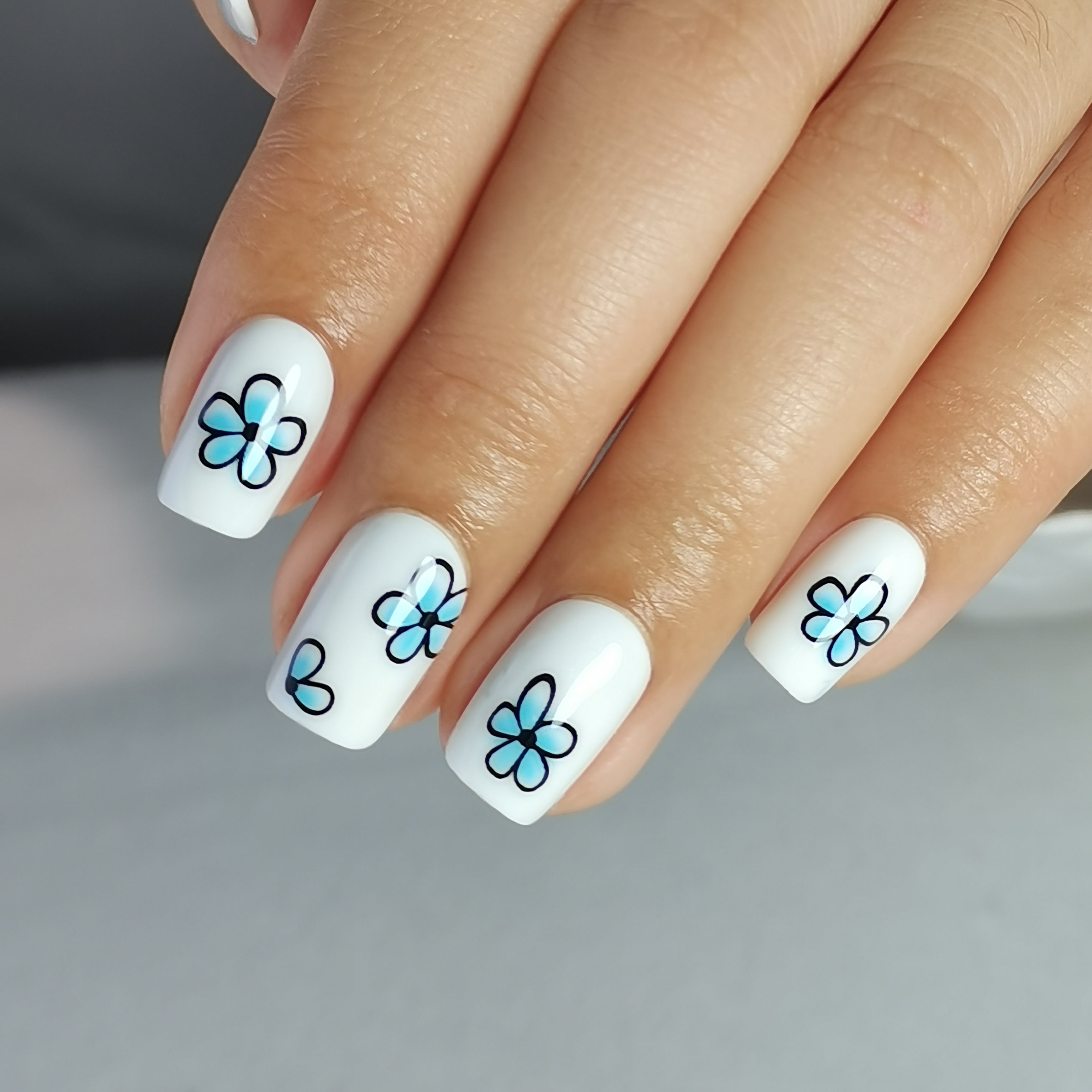 Sky Petals short squoval press-on nails worn on a hand