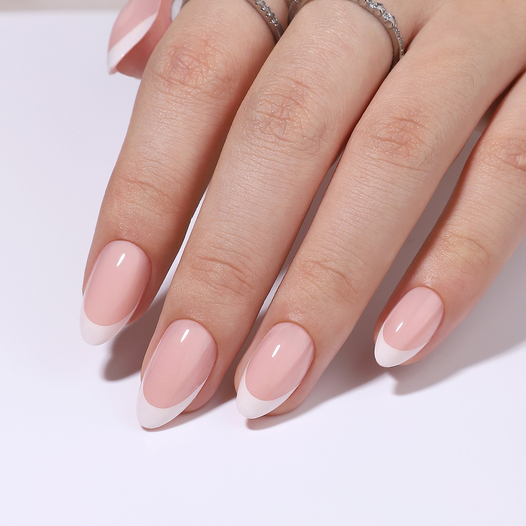 Soft French Glow short almond press-on nails worn on a hand