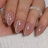 Soft Nude Charm short almond press-on nails worn on a hand