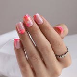 Sunset Blush short squoval press-on nails worn on a hand