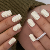 Sweater Embrace short squoval press-on nails worn on a hand